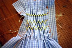 the blue and white checkered fabric is being sewn together with yellow thread on it