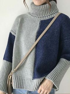 a woman wearing a gray and blue sweater holding a brown handbag in her right hand