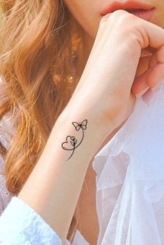 a woman with a small tattoo on her left wrist and the word love is written in black ink