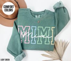 You will love this Comfort Colors sweatshirt for your Mimi.  This crewneck sweatshirt has a colorful design on the front of the sweatshirt that says Mimi.  This minimalist sweater will be perfect for your Mimi's Birthday, Mimi's Christmas or Mimi's Mother's Day.  Your Mimi will love wearing this trendy sweater this fall and winter season. Link to short sleeve t-shirt: https://etsy.me/3TPf3OW Link to Sweatshirt: https://etsy.me/3XGyUAN Link to Long Sleeve Shirt: https://etsy.me/3zCxb7A Attn: I am Cute Green Sweatshirt With Letter Print, Mimi Birthday, Minimalist Sweater, Mimi Gift, Trendy Sweater, Comfort Colors Sweatshirt, Trendy Sweaters, Colorful Design, Winter Season