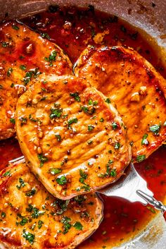 grilled pork chops with sauce and parsley in a skillet ready to be eaten