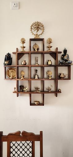 a wooden shelf filled with lots of different items on top of a wall next to a chair