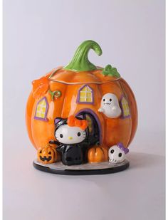 a hello kitty figurine sitting on top of a pumpkin with two cats in it