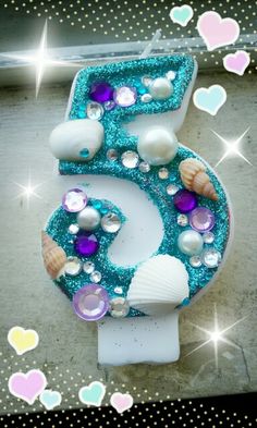 the number six is decorated with seashells, pearls and other sea creatures in blue glitter