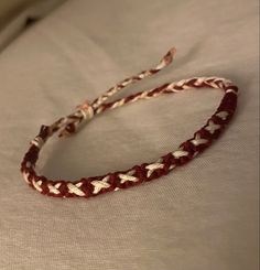 a red and white braided headband laying on top of a bed next to a pillow