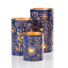 three blue candle holders with gold stars and sparkles on them, set against a white background