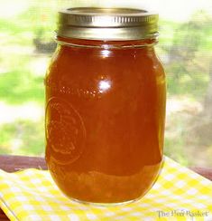 a glass jar filled with honey sitting on top of a yellow and white checkered napkin