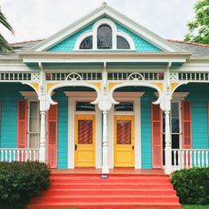 a blue and yellow house with red steps leading up to the front door that is painted in bright colors