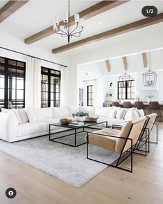 a living room filled with white furniture and wooden beam ceiling beams in an open floor plan