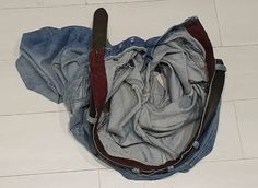 an old pair of jeans sitting on the floor next to a knife in a pocket