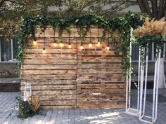 a wooden fence with lights hanging from it's sides and some plants growing on the side