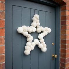 a white star hanging on the side of a door with pom - poms