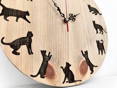 a wooden clock with black cats on it