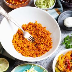 an assortment of mexican food including rice, beans and guacamole are on the table