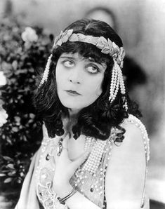 a woman in an old photo with pearls and beads on her head is posing for the camera