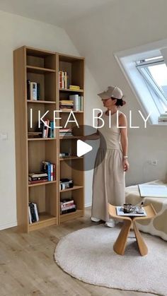 a woman standing in front of a book shelf next to a couch and coffee table