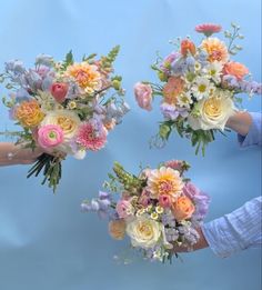 three bouquets of flowers are being held by someone's hands on a blue background