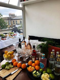 an assortment of alcohol and fruit on a table with a cityscape in the background