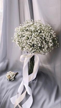 a bouquet of baby's breath tied to a white ribbon on a gray background