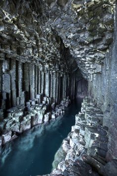 the inside of a cave with blue water in between it and rocks on either side