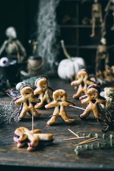 there are many small cookies that look like people on the table with sticks in their hands