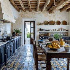 a kitchen with blue cabinets and tile flooring next to a wooden table topped with fruit