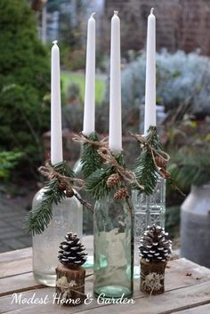 candles and pine cones in glass bottles on a table