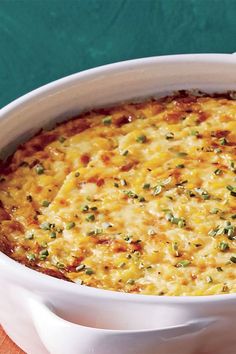 a white casserole dish with cheese and herbs in it on a green table