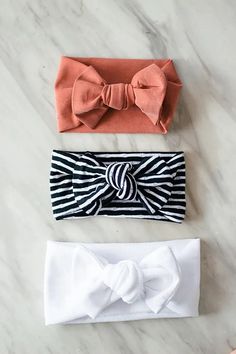 three headbands with bows on them sitting next to each other in front of a marble surface