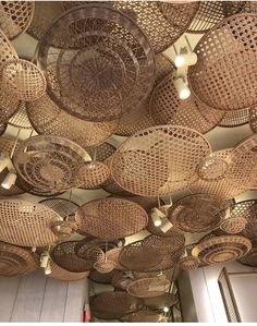 many woven baskets are hanging from the ceiling