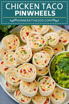 a plate full of taco pinwheels with guacamole on the side