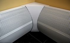 two white speakers sitting next to each other on top of a table in front of a yellow wall