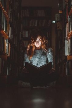 a woman sitting on the floor in front of bookshelves with her eyes closed