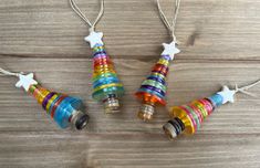 three colorful christmas tree ornaments hanging from strings on a wooden table with string attached to them