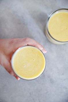 two people holding glasses filled with yellow liquid