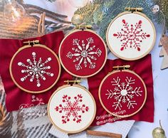 three cross stitch snowflakes on red fabric