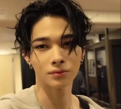 a young man with black hair and piercings on his ears looking at the camera