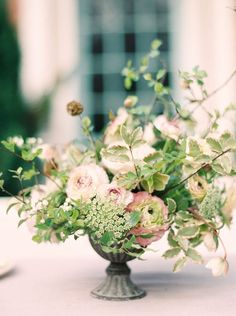 a vase filled with lots of flowers on top of a white tablecloth covered table