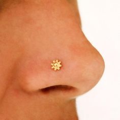 a close up of a person's nose with a tiny gold flower on it