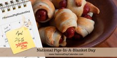 hot dogs wrapped in crescented bread on a plate next to a calendar with the national pig - in - a - blanket day