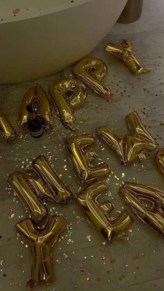 gold foil balloons spelling out happy new year on the floor next to a bathtub