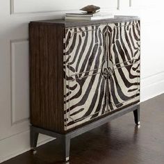 a zebra print cabinet in the corner of a room with white walls and wood floors