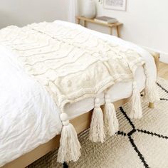 a white bed with tassels on the headboard and foot board in a bedroom