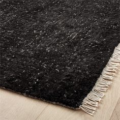 a black rug with fringes on the floor