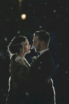 a bride and groom are standing in the snow at night with their foreheads touching each other