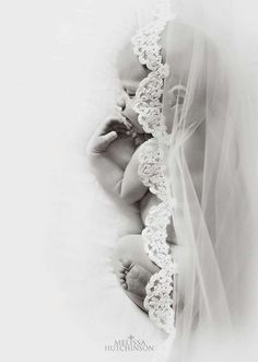 a black and white photo of a baby wrapped in a veil