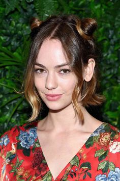 a close up of a person wearing a flowered dress and hair in a bun