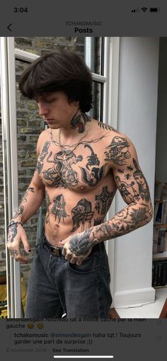 a man with tattoos on his chest and arm is standing in front of a window