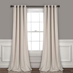 a white curtain hanging on the side of a window next to a wooden floor and wall