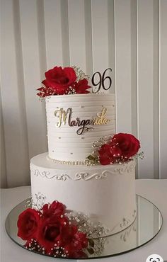 a white cake with red roses on top and the number sixty written in gold lettering